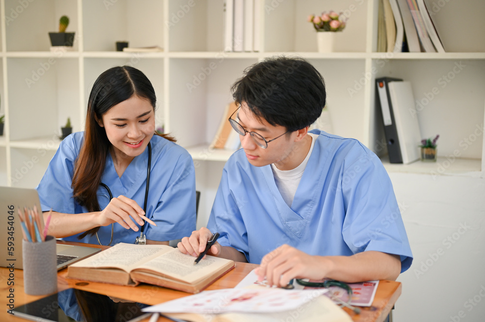 Two medical students are studying and researching medical information at the library together. Two medical students are studying and researching medical information at the library together.
