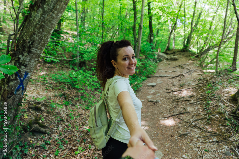 a woman with a backpack walks on the road in the woods hiking journey on foot a woman with a backpack walks on the road in the woods hiking journey on foot