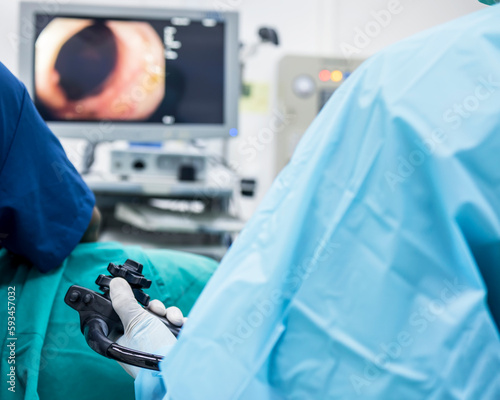 A doctor or surgeon in a light blue protective gown did a colonoscopy or gastroscopy inside operating theatre in the hospital.EGD technology for cancer screening.Blur green background and foreground. photo