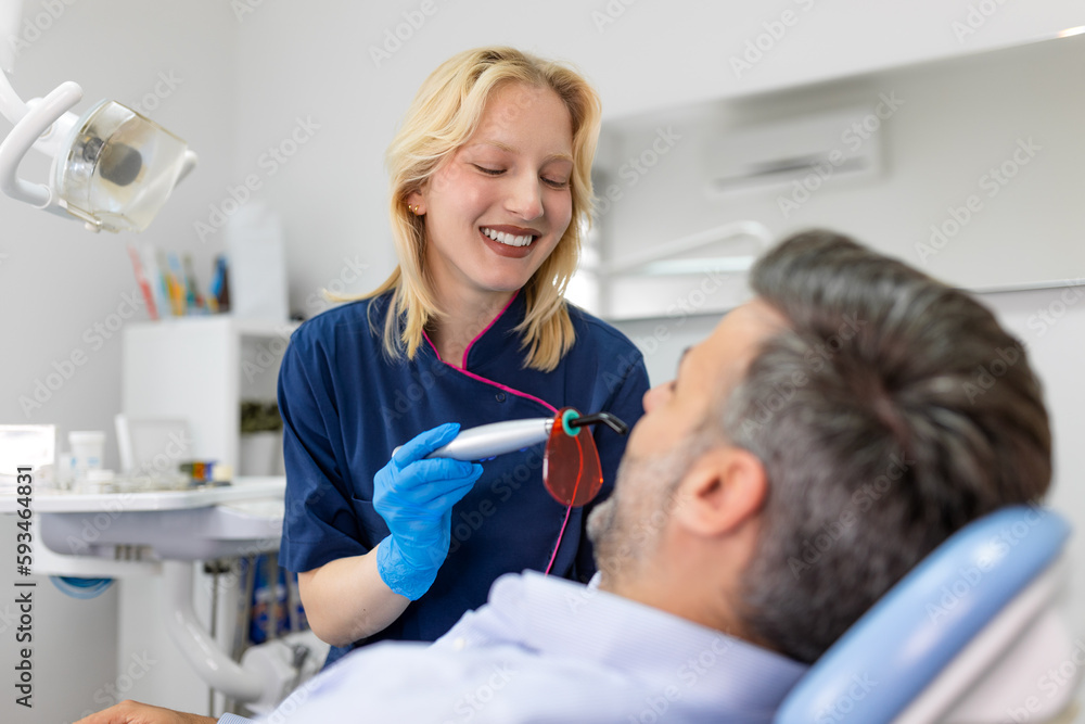 Patient in the dental clinic. Teeth whitening UV lamp with photopolymer composition. Man during teeth whitening procedure with curing UV light at dentist's office. Patient in the dental clinic. Teeth whitening UV lamp with photopolymer composition. Man during teeth whitening procedure with curing UV light at dentist's office.