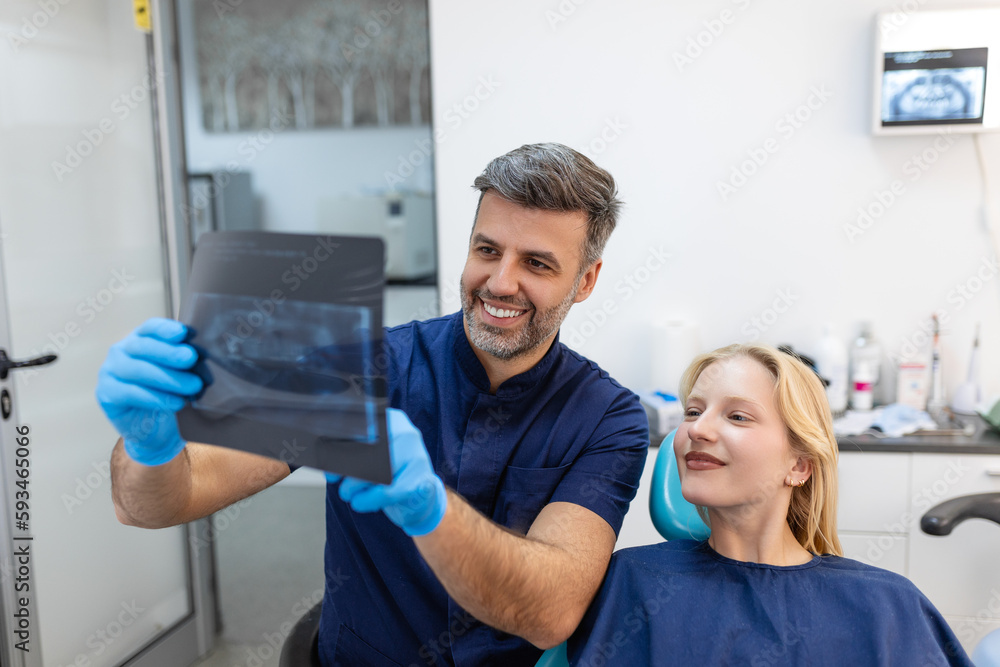 Doctor talking with her patient and teaching a radiograph. Dentist concept of woman sitting in a dental chair while her dentist reads out an x-ray scan Doctor talking with her patient and teaching a radiograph. Dentist concept of woman sitting in a dental chair while her dentist reads out an x-ray scan