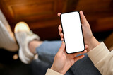 Top view of a woman in casual clothes using her smartphone while chilling in a coffee shop