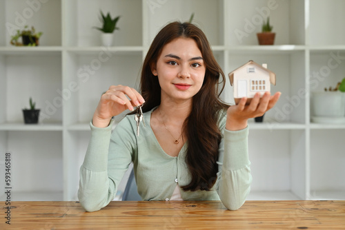 Millennial Caucasian girl holding mockup house and keys. Real estate investing, financial planning, first home purchase, mortgage, home refinance concept.