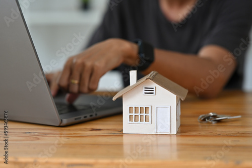 Financial planning, investment, real estate, residential house concept. Close up of mockup house and key placed on home brokers desk.