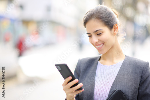 Happy executive using cell phone in the street