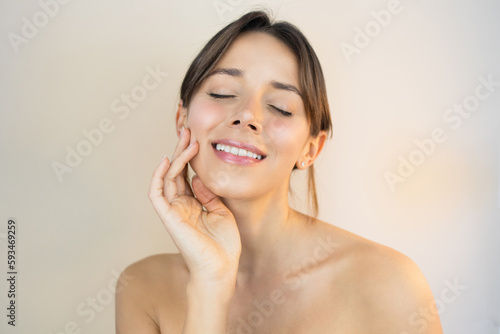 Young Woman With Glowy Skin Eyes Closed Touching her Face with Flawless Healthy and Bright No-Makeup Makeup Look