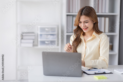 Asian Business woman using calculator and laptop for doing math finance on an office desk, tax, report, accounting, statistics, and analytical research concept
