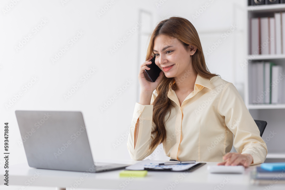 Cheerful business Asian woman freelancer making telephone call share good news about project working in office workplace, business finance concept.	