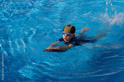 Canvas Print 6 years old young boy who a swimmer wearing goggle with dark blue suit and yellow striped black cap