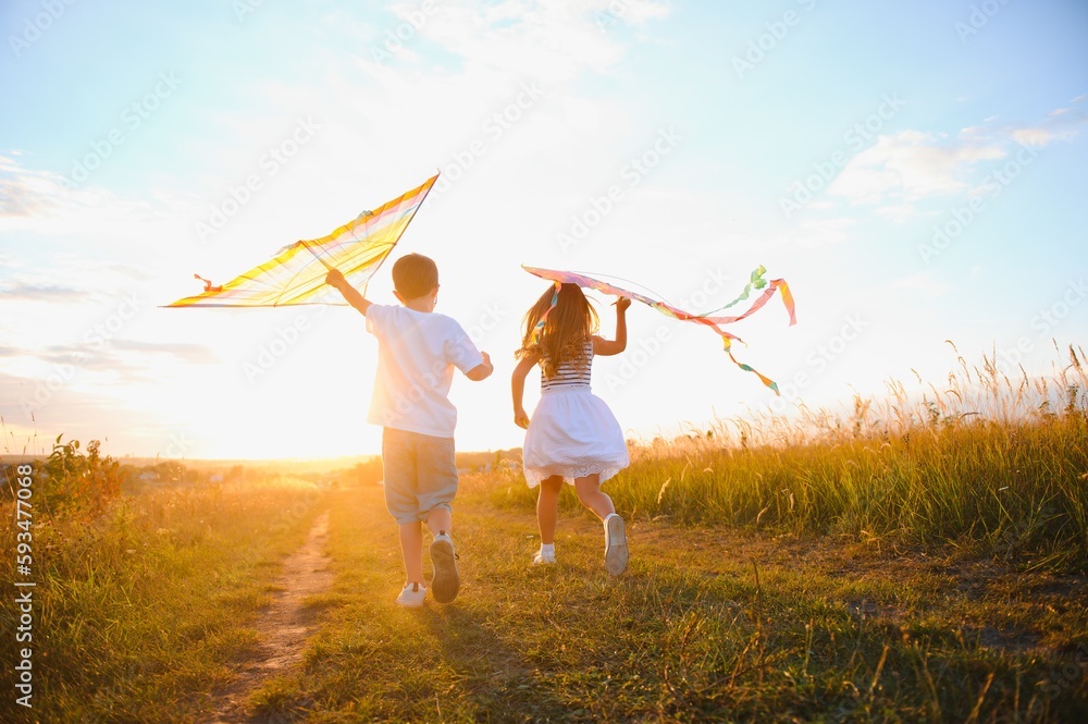 Happy children launch a kite in the field at sunset. Little boy and girl on summer vacation. Happy children launch a kite in the field at sunset. Little boy and girl on summer vacation.