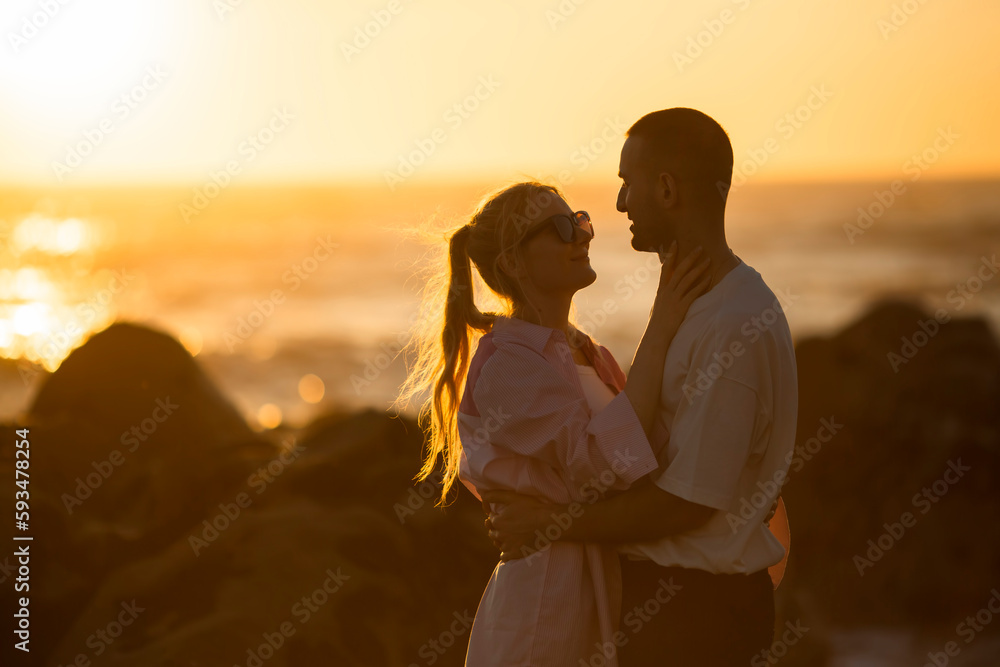 A young couple in love on the ocean during a golden sunset.