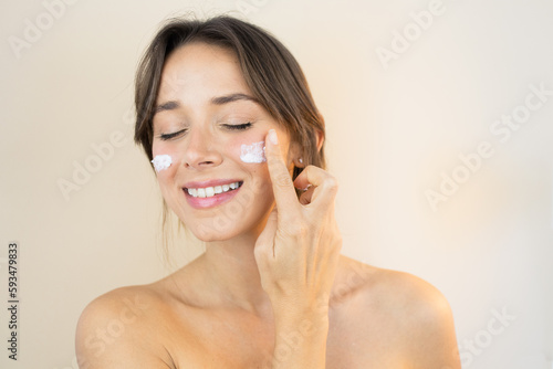 Fotografi Young Woman With Face Cream Moisturizer with Glowing Skin Plump and Smooth Skin