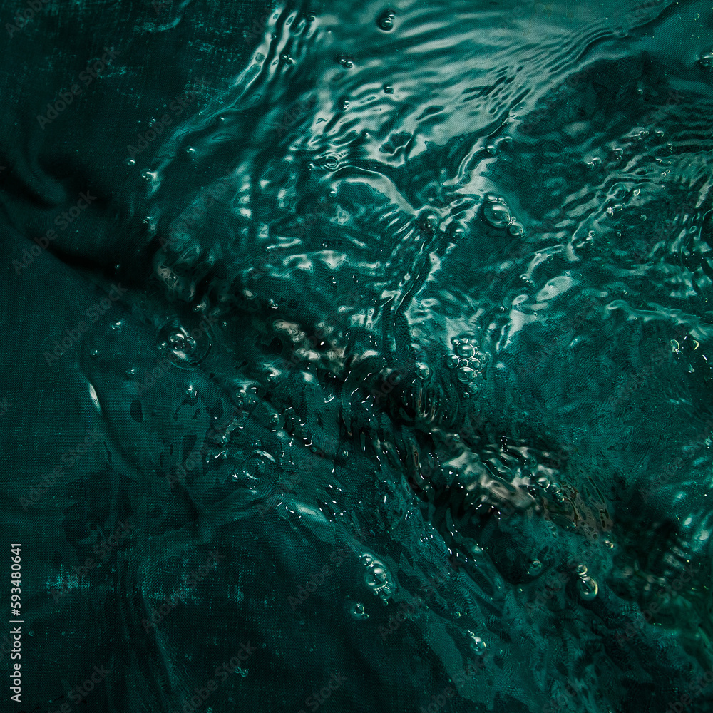 A dark green fabric with folds lies underwater with waves and splashes. Image for your creative design or stylish illustrations. A dark green fabric with folds lies underwater with waves and splashes. Image for your creative design or stylish illustrations.