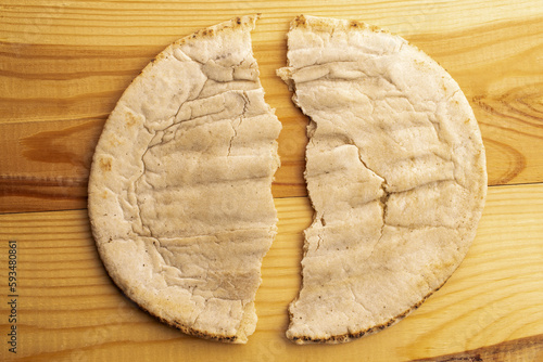 One baked pita, close-up, on a wooden table, top view.