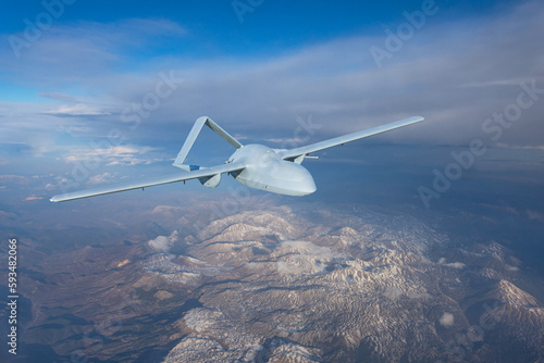 Unmanned military drone uav flying in the air, reconnaissance flight over the territory above the snow-capped mountains hills relief.