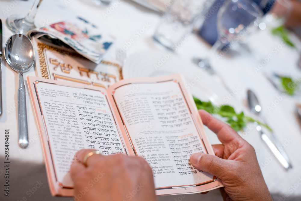 Obraz premium Man's hands holds book. Holiday of Jewish people, Matzo national food served on table on special plate. Traditionally Passover celebrate with red wine. Israel, april, 05, 2023