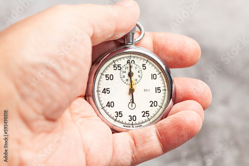 stopwatch in hand on a gray background