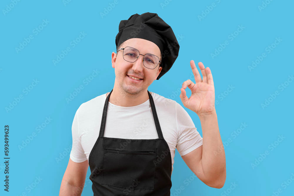 Young smiling chef in uniform on a blue background. Cooking concept. Young smiling chef in uniform on a blue background. Cooking concept.