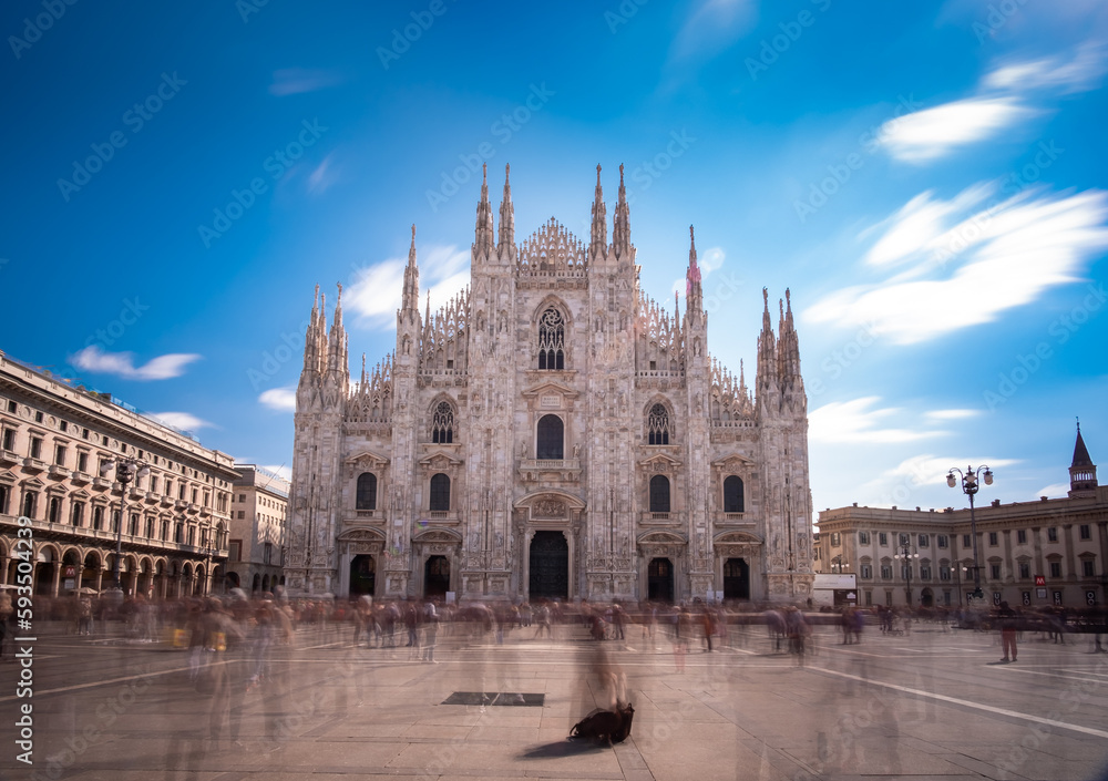 Long time exposure of Milan cathedral (Duomo di Milano) front on a sunny day with people moving across the square