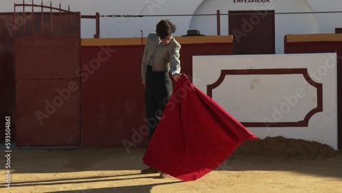 Bullfighter dressed in traditional costume practicing with the cape in bullring