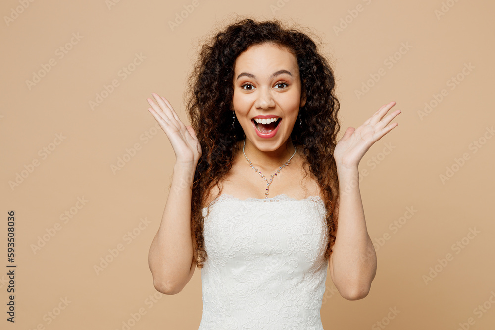 Beautiful stunned happy young woman bride wear white wedding dress posing look camera spread hands isolated on plain pastel light beige background studio portrait. Ceremony celebration party concept. Beautiful stunned happy young woman bride wear white wedding dress posing look camera spread hands isolated on plain pastel light beige background studio portrait. Ceremony celebration party concept.