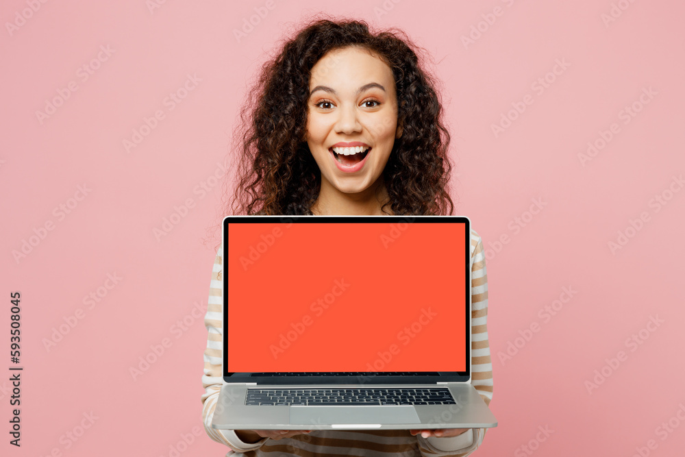 Naklejka premium Young IT woman of African American ethnicity wear light casual clothes hold use work on laptop pc computer with blank screen workspace area isolated on plain pastel pink background studio portrait.