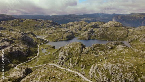 Aerial view over lush, green nature and hills, towards steep mountains, landscape moving slowly while floating above glacial lakes and mountain hills. Drone shot near Lysebotn, Norway photo