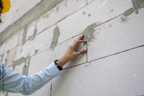 Asian engineer in uniform at construction site while checking and inspecting concrete material for house building. Professional engineering manager working on structure building at workplace.