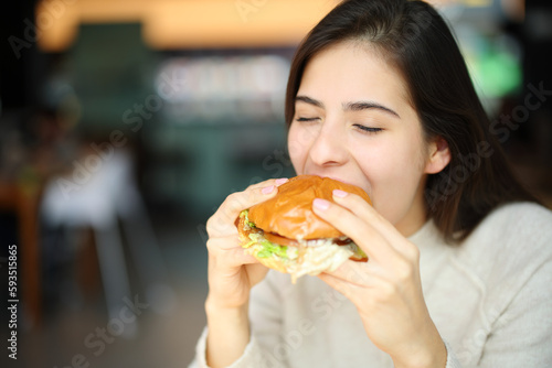 Woman eating burger in a restaurant