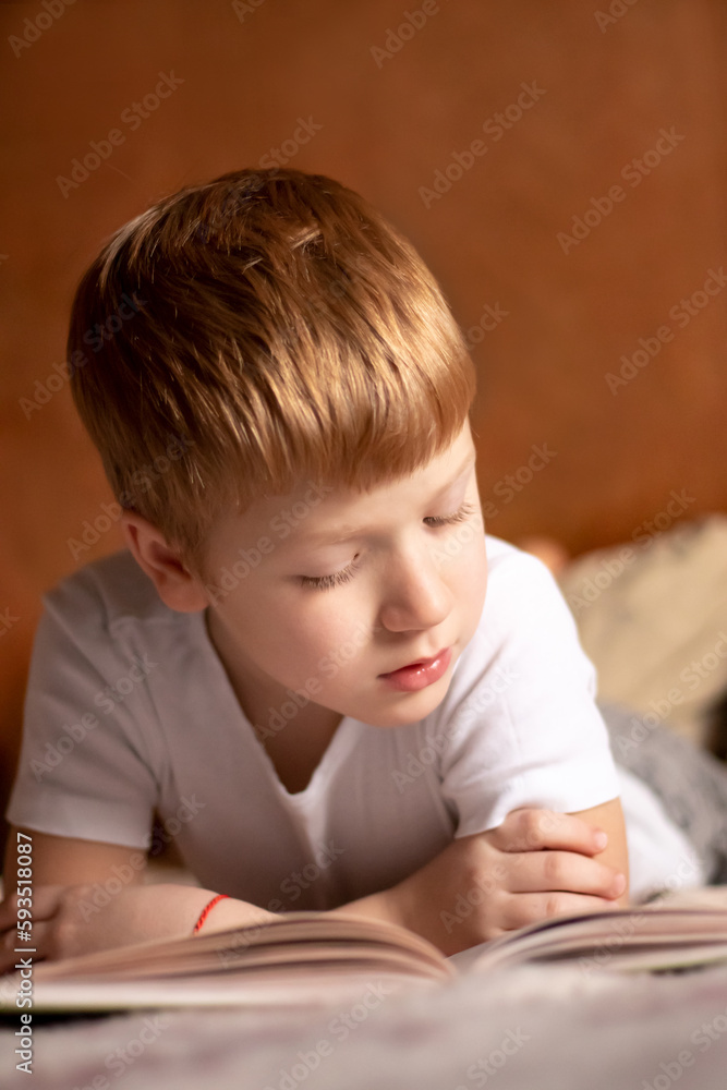 teenager boy lying on the bed and reading a book teenager boy lying on the bed and reading a book