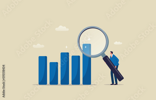 Businessman using giant magnifying glass to analyze bar graph for market research.