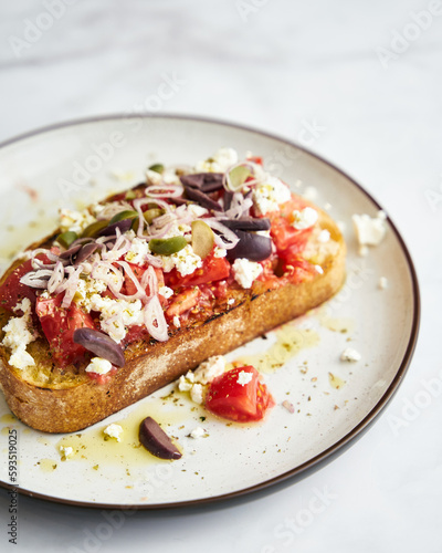 Dakos salad traditional Greek salad with soaked and crunchy barley rusks or bread, topped with juicy tomatoes, feta cheese, onions, olives, and a drizzle of olive oil. Popular apetizer