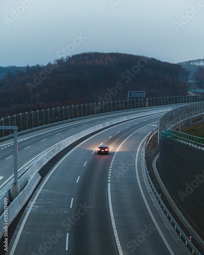 Car driving on an empty highway with lights on, verticall photo