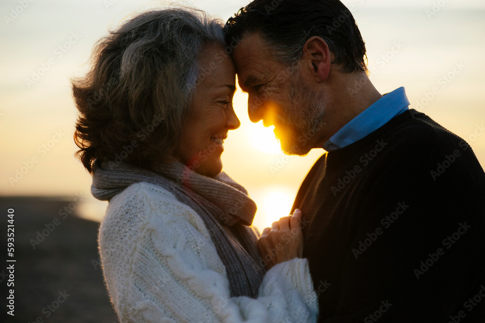 Smiling woman embracing man at sunrise