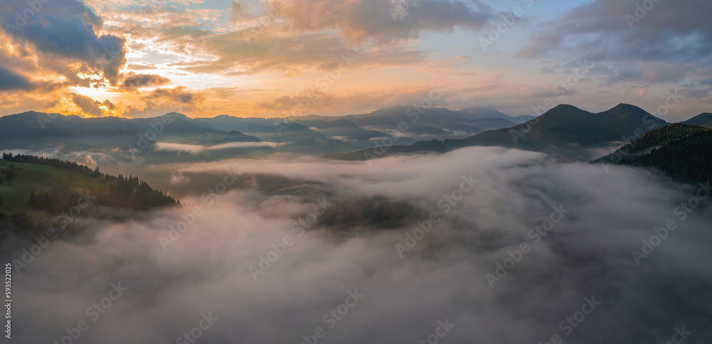 Mountains in clouds at sunrise in summer. Aerial view of mountain peak with green trees in fog. Beautiful landscape with high rocks, forest, sky. Mountains in clouds at sunrise in summer. Aerial view of mountain peak with green trees in fog. Beautiful landscape with high rocks, forest, sky.