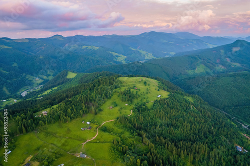 Scenic aerial view of the foggy Carpathian mountains, village and blue sky with sun and clouds in morning light, summer rural landscape photo