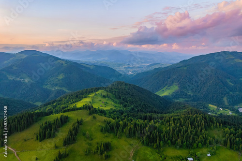 Fototapeta Naklejka Na Ścianę i Meble -  Mountains in clouds at sunrise in summer. Aerial view of mountain peak with green trees in fog. Beautiful landscape with high rocks, forest, sky.