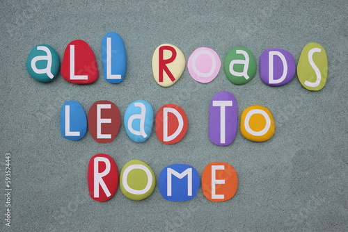 All roads lead to Rome, italian proverb composed with hand painted stone letters over green sand