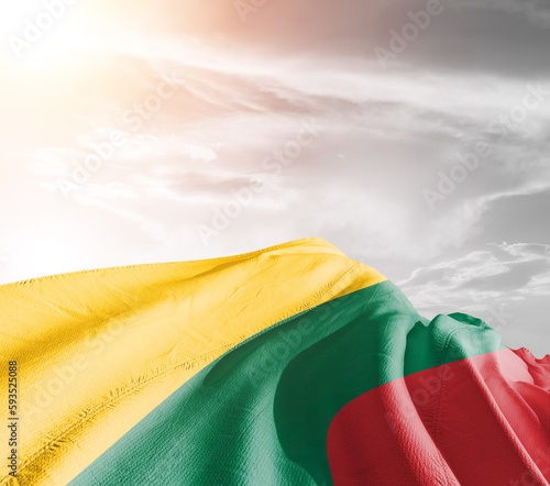 Lithuania national flag cloth fabric waving on beautiful sky grey Background.
