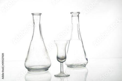 Transparent glass bottles and a small glass goblet isolated on the empty white background