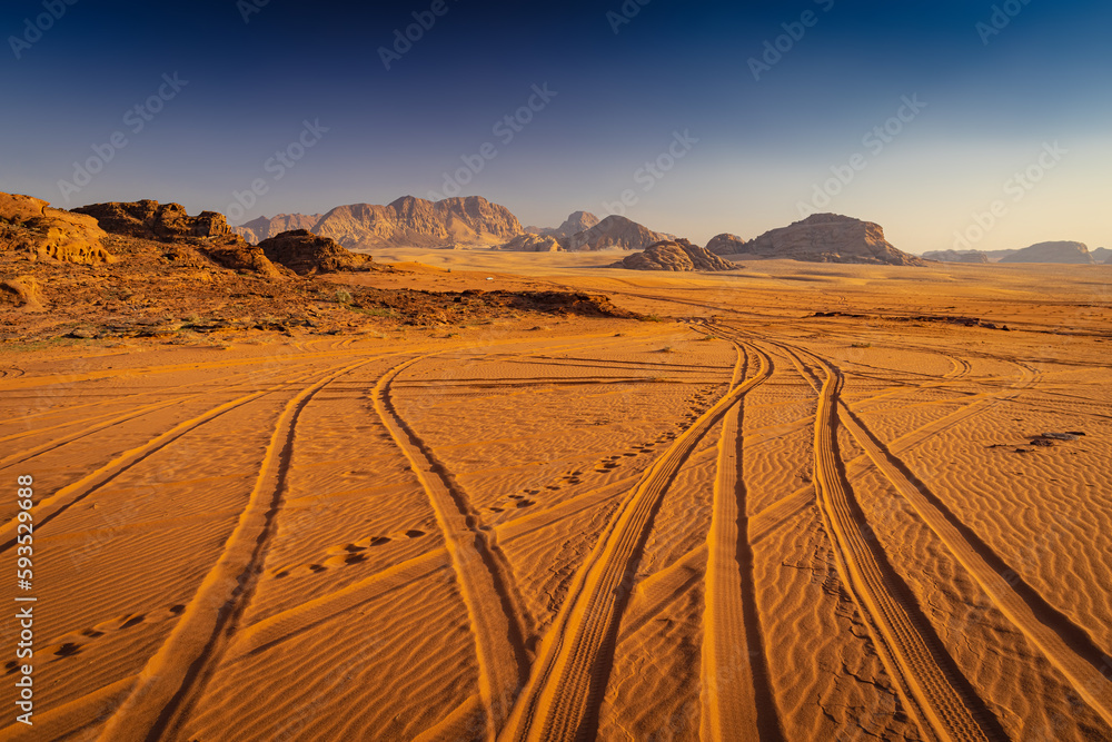 Wadi Rum w Jordanii. Ślady opon samochodowych na pustynnym piasku. - obrazy, fototapety, plakaty 