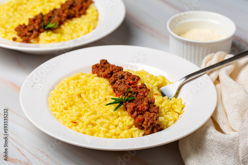 Close-up of risotto alla milanese or risotto allo zafferano with meat ragu sauce. Italian dish made from saffron, rice, butter, hard cheese and vegetable broth. White table. Top view.