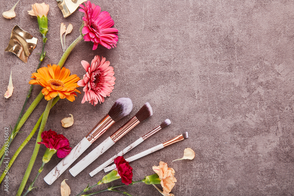 Aesthetic make up brushes set among arrangement of gerbers, asters flowers with copy space. Makeup artist professional tools