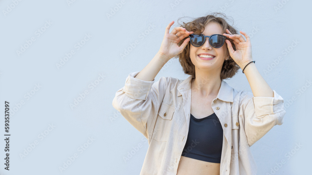 Young woman in sunglasses over gray wall background. Summer day. Young woman in sunglasses over gray wall background. Summer day.