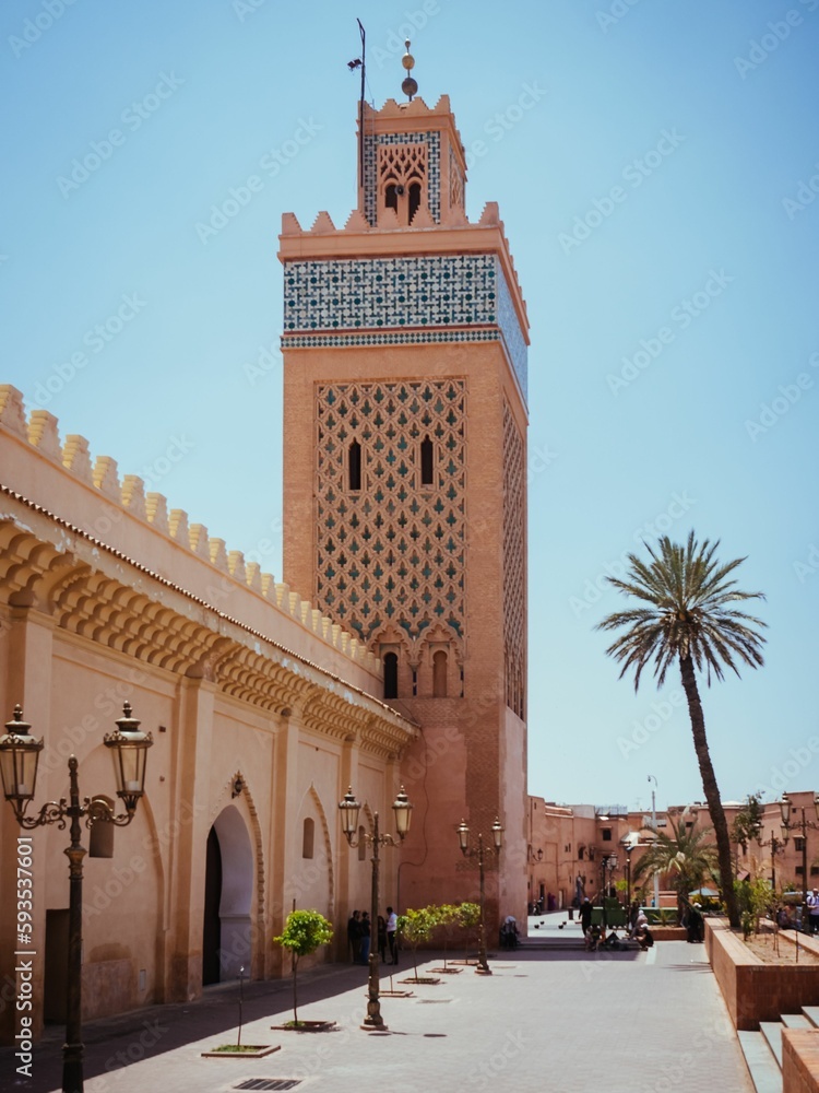 Tower with palm trees under the blue sky in Morocco.