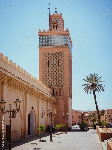 Tower with palm trees under the blue sky in Morocco.