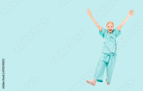 Full body Cheerful Elderly patient woman wearing patient uniform looking to camera Old lady raised hands and leg dance Health care and Insurance concept isolated over green background copy space