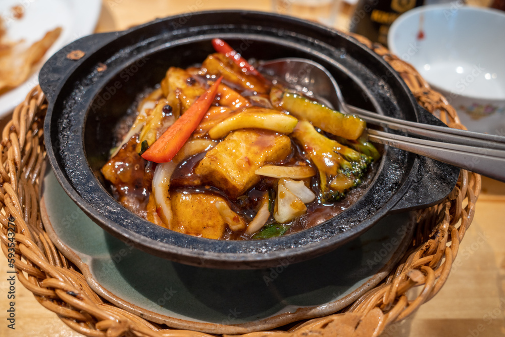 A typical Cantonese Chinese hot pot dish with Szechuan spices and tofu in an iron pot at a restaurant. A typical Cantonese Chinese hot pot dish with Szechuan spices and tofu in an iron pot at a restaurant.