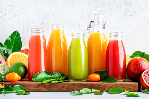 Summer beverages. Citrus fruit juices, fresh and smoothies, food background. Mix of different whole and cut fruits: orange, grapefruit, lime, tangerine with leaves and bottles with drinks