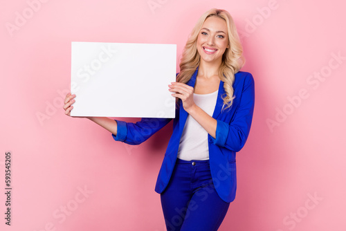 Portrait of cheerful lady toothy smile arms hold empty space paper blank isolated on pink color background